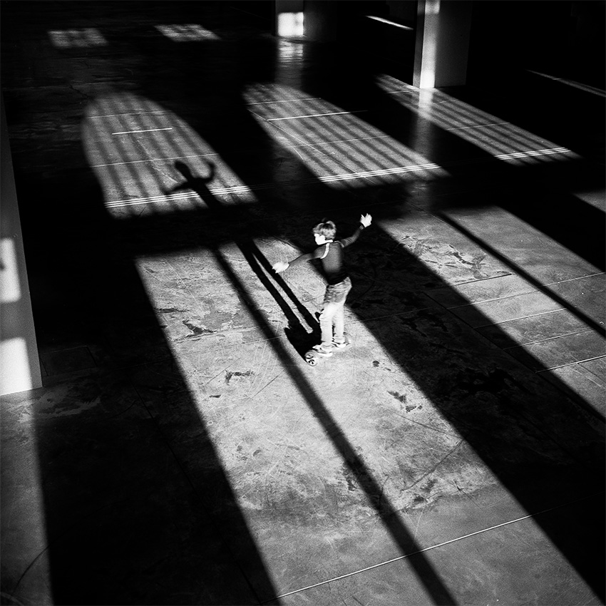 Brest, halle des Capucins. Un enfant sur un engin à roulettes projette une ombre longue sur le sol.