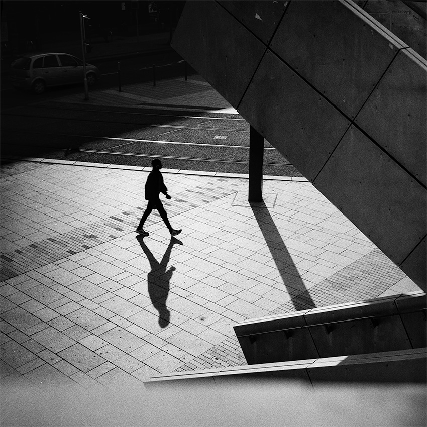 Place de Strasbourg, un homme marche et projette une ombre sur le sol